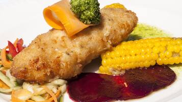 A plated meal with a breaded item, corn, and a beetroot slice.
