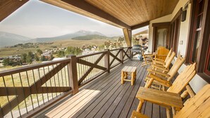Una terraza de madera con vistas a un valle y montañas.