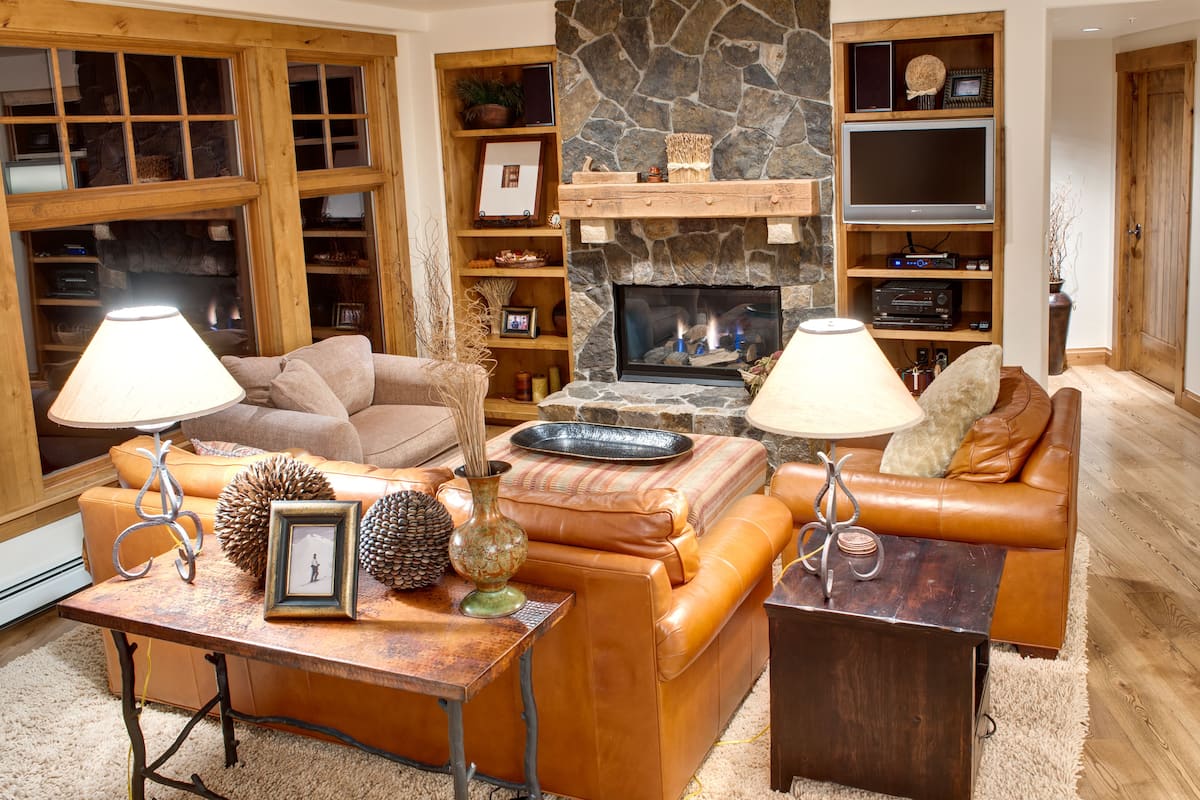 Una sala de estar acogedora con sofás de cuero, una chimenea de piedra y estanterías de madera.