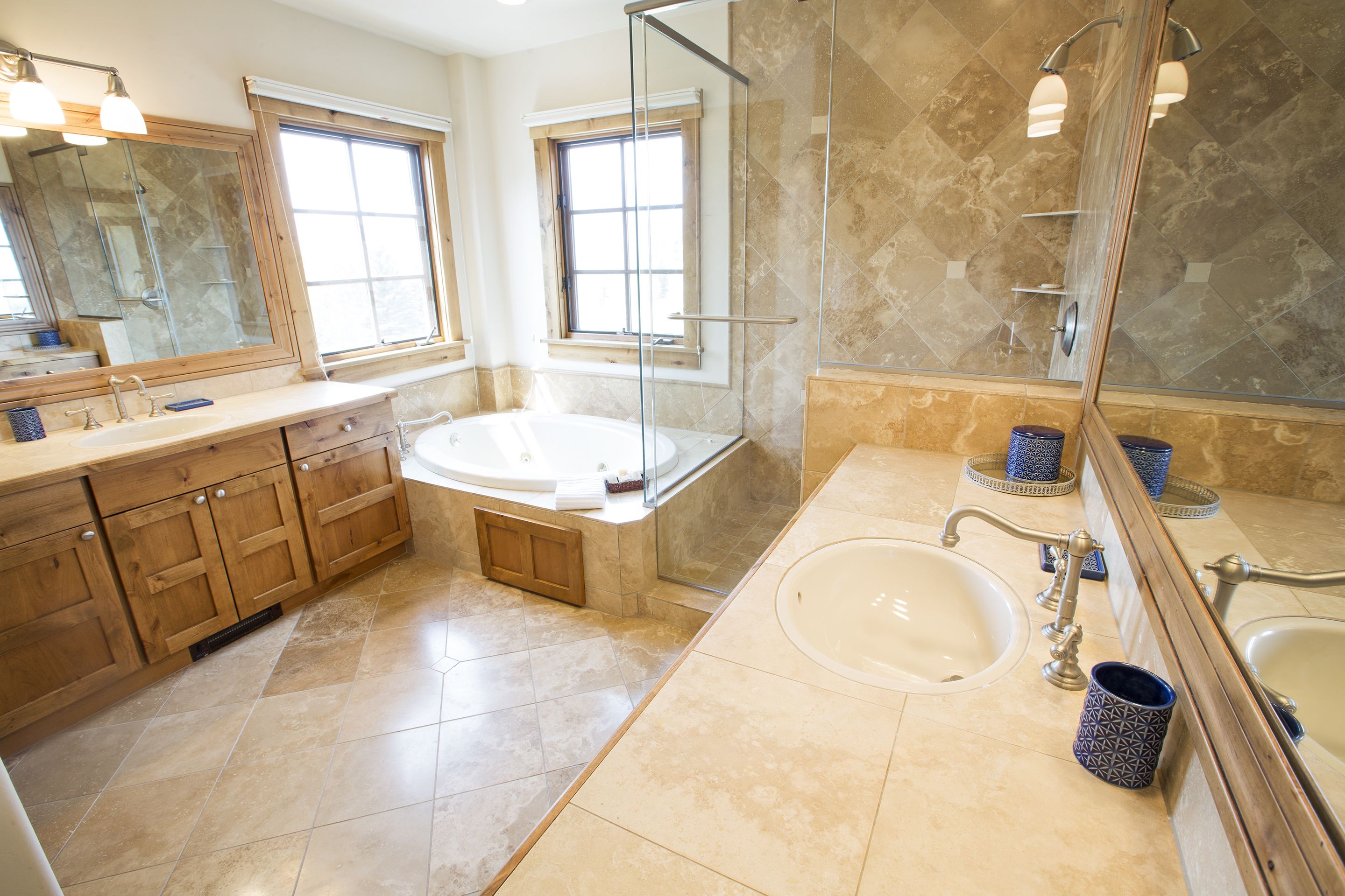 A modern bathroom with a large bathtub, two sinks, and a walk-in shower.