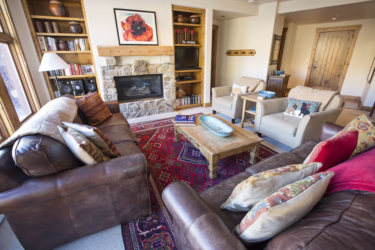 Una sala de estar acogedora con sofás de cuero, una chimenea, estanterías y una mesa de centro.