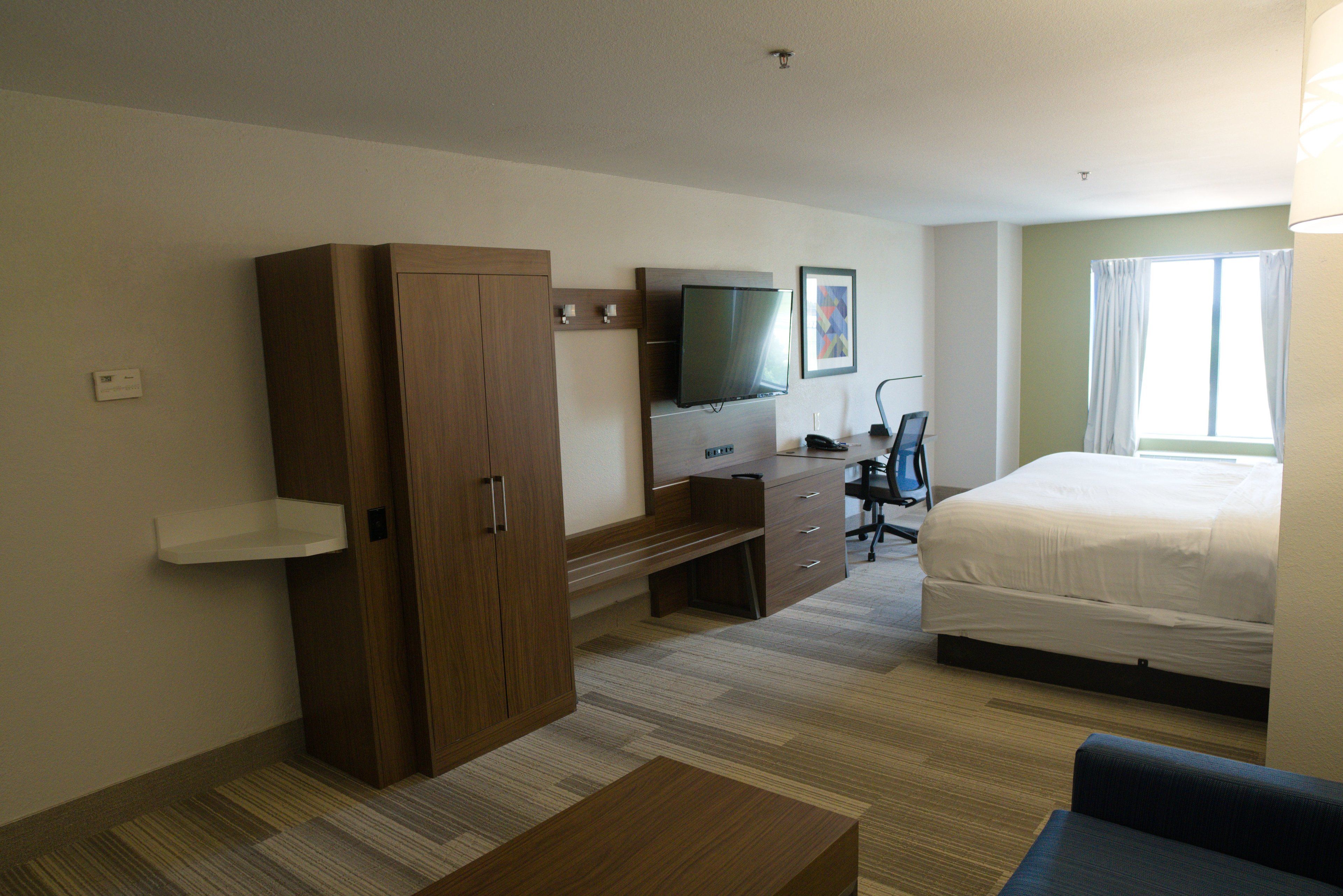 Een hotelkamer met een bed, een televisie, een bureau en een kledingkast.