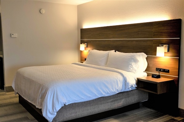 A hotel room with a bed, bedside tables, and a wall-mounted light fixture.