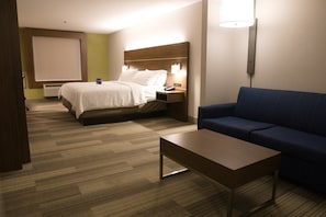 A hotel room with a bed, a sofa, a coffee table, and a TV.