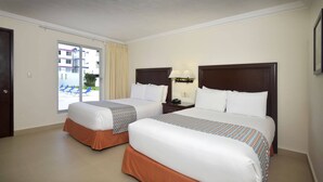 A hotel room with two beds, a window with curtains, a nightstand with a lamp, and a view of the outside. - Hotel Bonampak (Cancun)