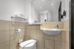 Features a sleek sink, toilet, and towel rack, with a mirror above the sink.