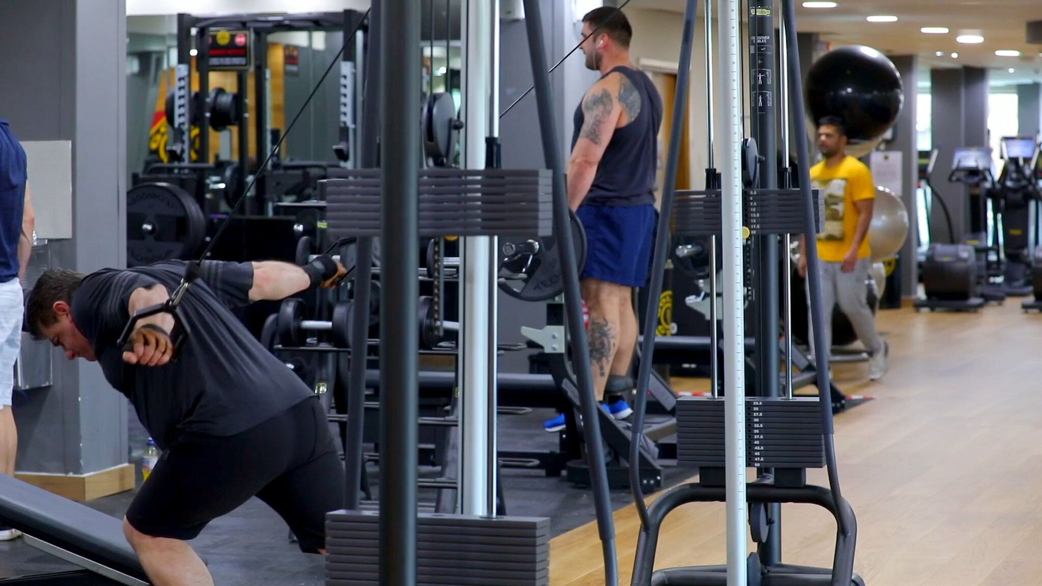 Een sportschool met diverse fitnessapparaten, waaronder krachtapparaten en loopbanden.