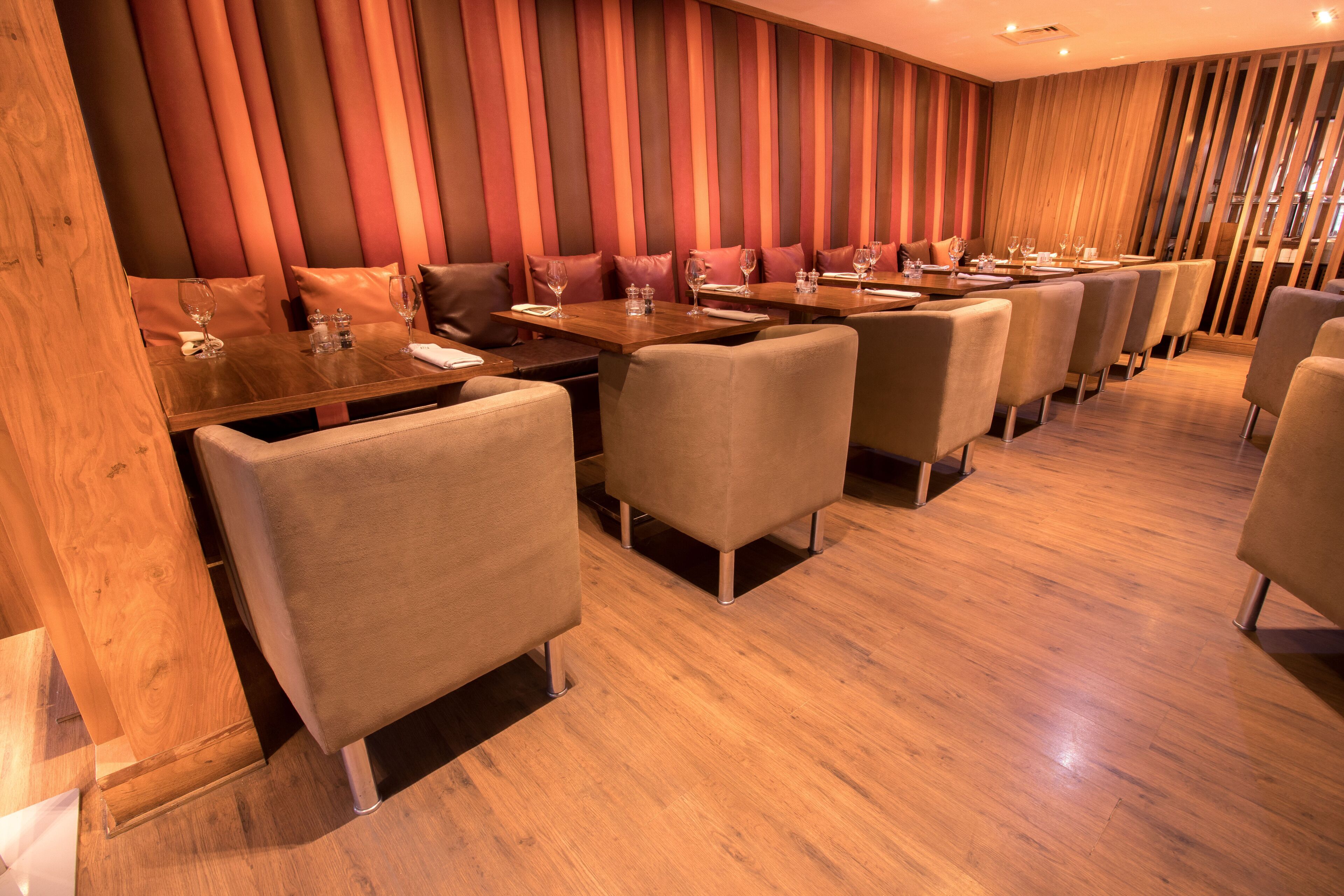 A restaurant with wooden flooring, cushioned booths, and tables set for dining.