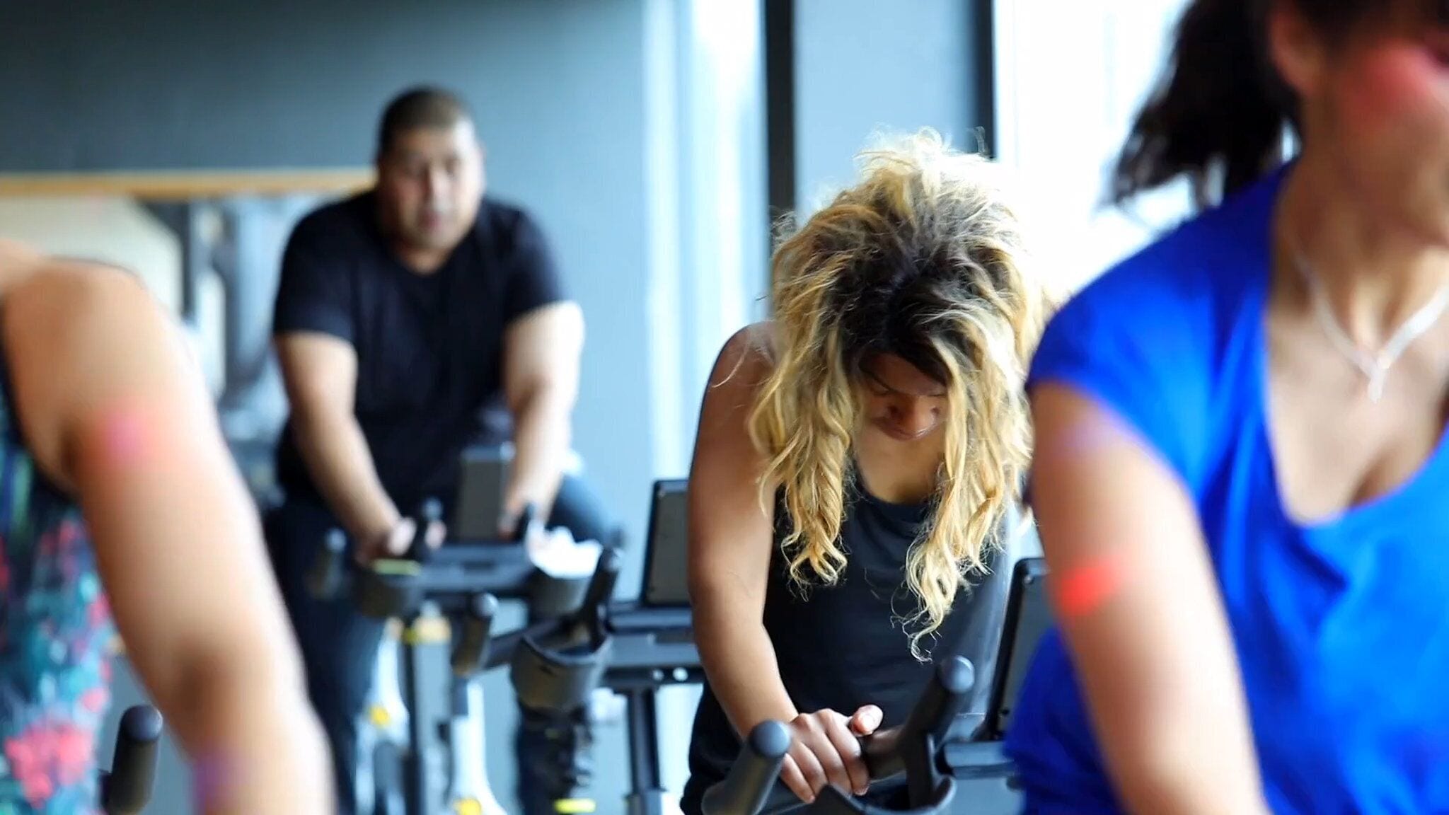 A gym with stationary bikes and a person using one.