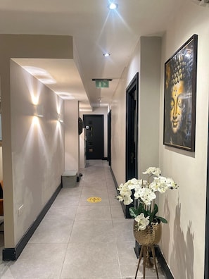 A hallway with a Buddha painting, a potted orchid, and a tiled floor. - The Continental Hotel and Spa, Heathrow (Hounslow)