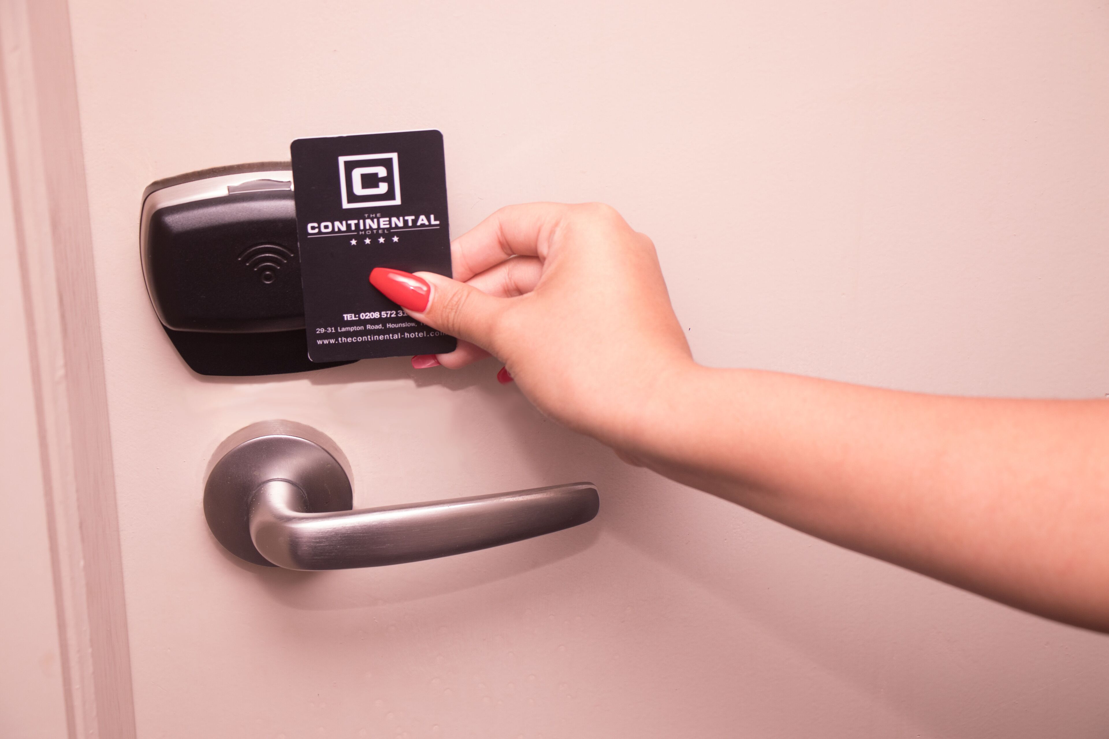 A hand holding a Continental hotel card near a door lock.