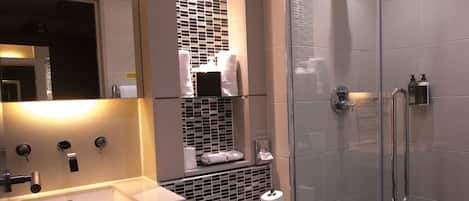 Un baño moderno con cabina de ducha de vidrio, un lavabo blanco y un inodoro.