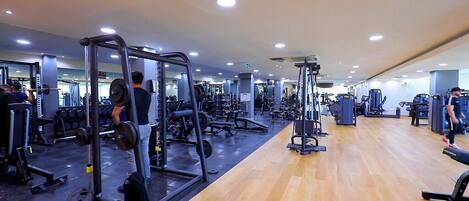 Un gimnasio con diversos equipos de ejercicio, incluyendo máquinas de pesas y pesas libres.