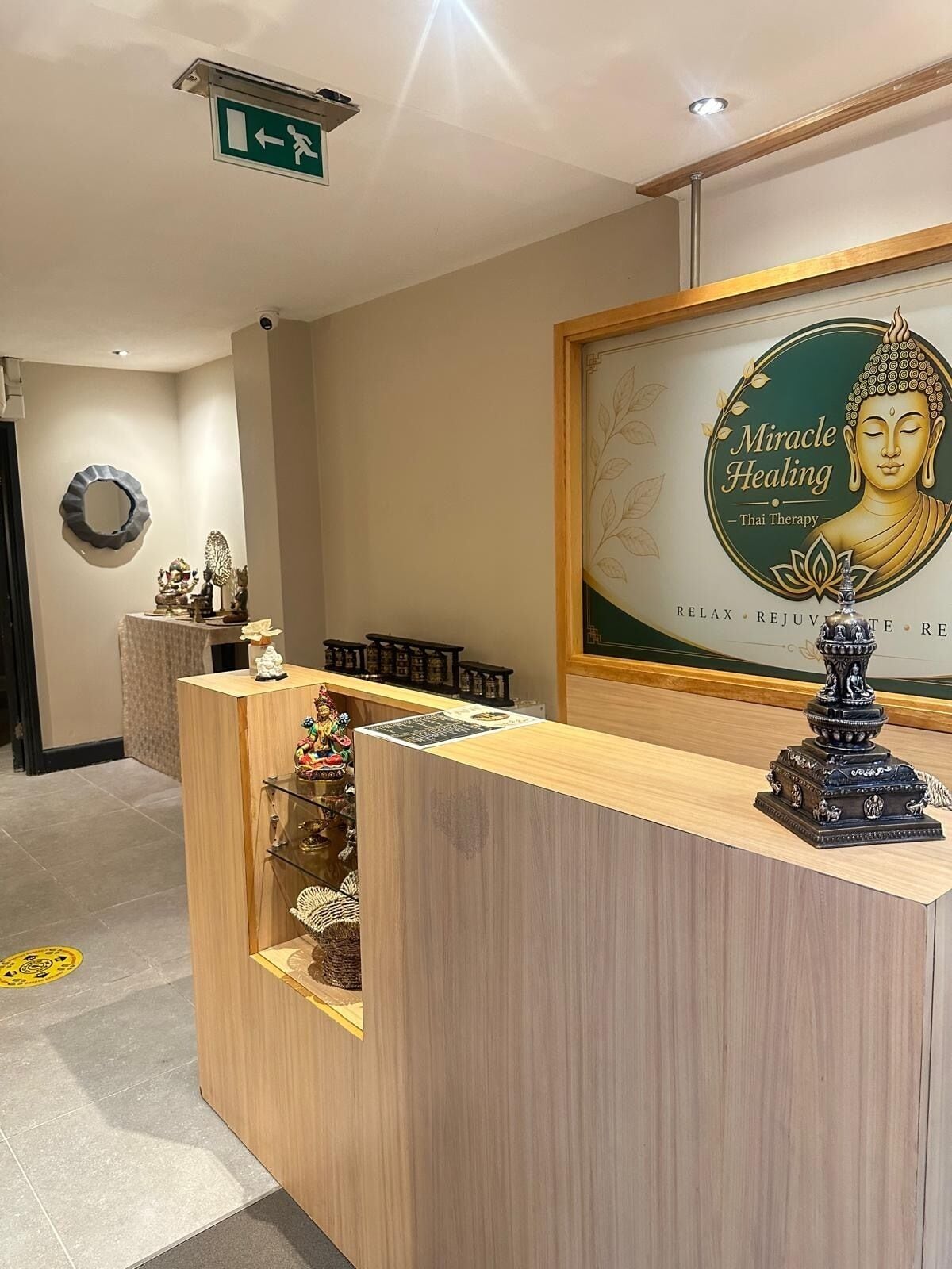 Ein Empfangsbereich mit einem gerahmten Poster eines Buddha, einer kleinen Buddha-Statue und einem Spiegel an der Wand.