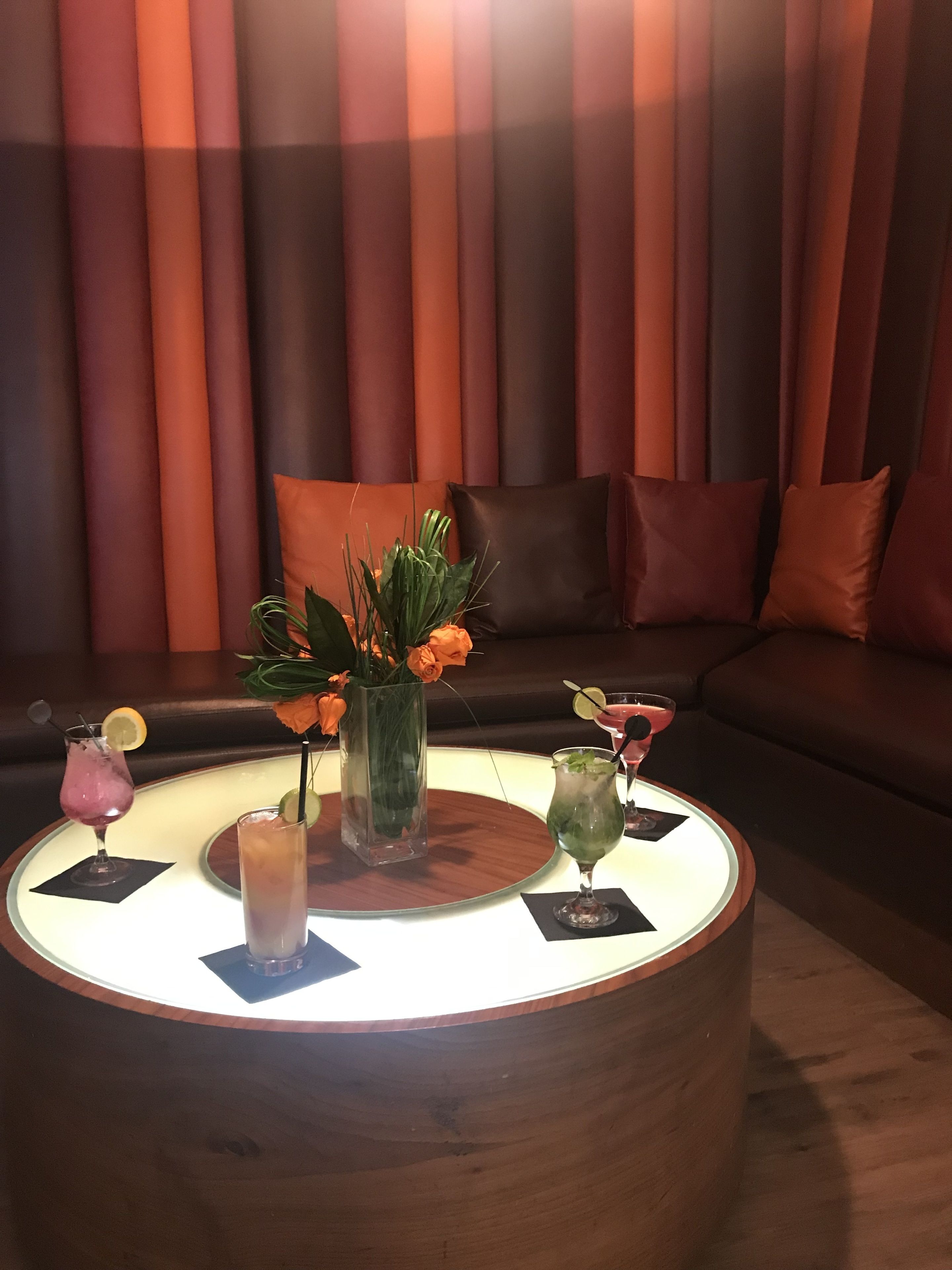 Una sala de estar moderna con una mesa de centro redonda, un sofá y un ventanal con persianas verticales.