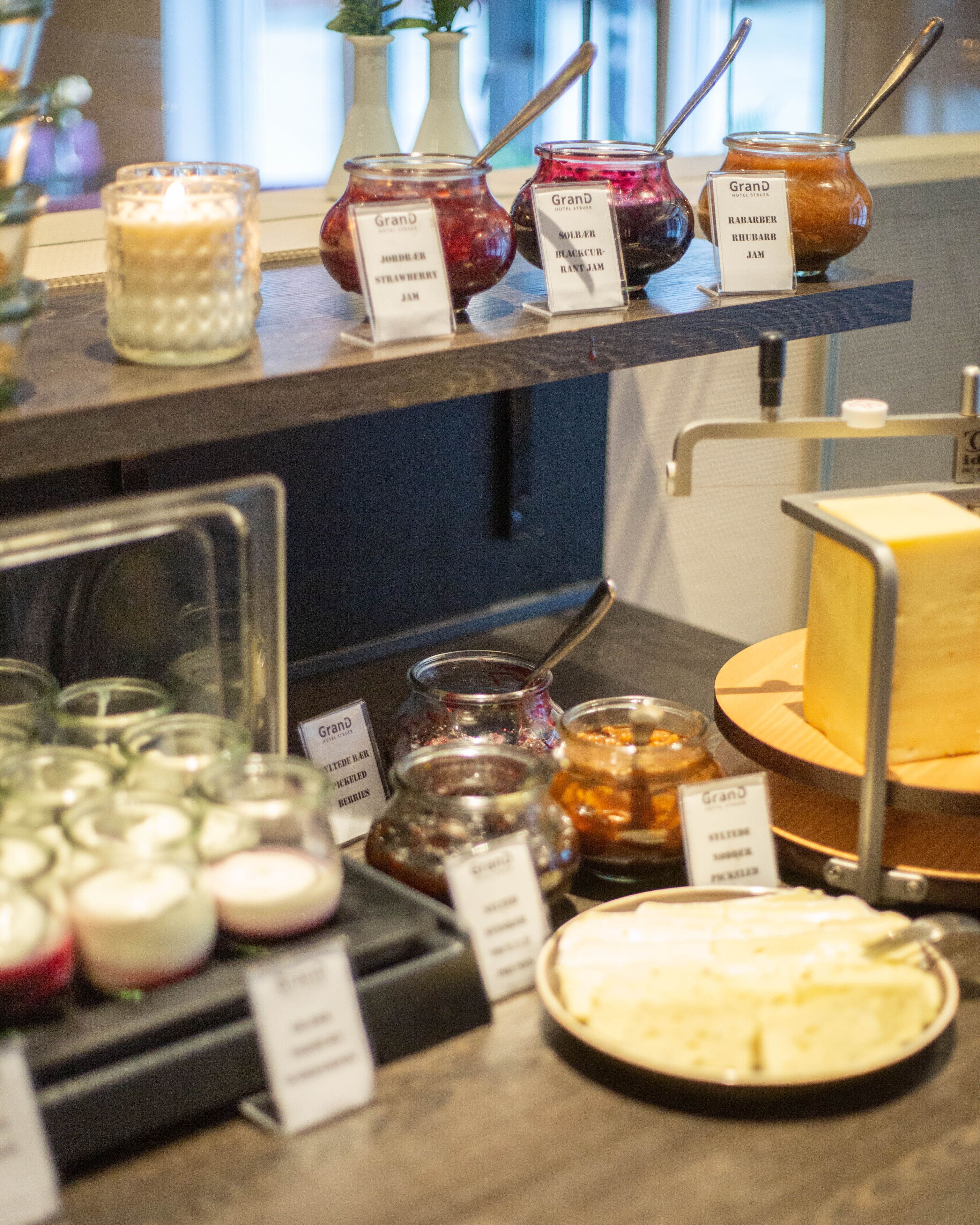A buffet with various jams, pickled berries, and a cheese platter.
