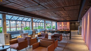 A modern lounge area with comfortable seating, large windows, and a view of the city. - Grand Hotel Struer (Struer)