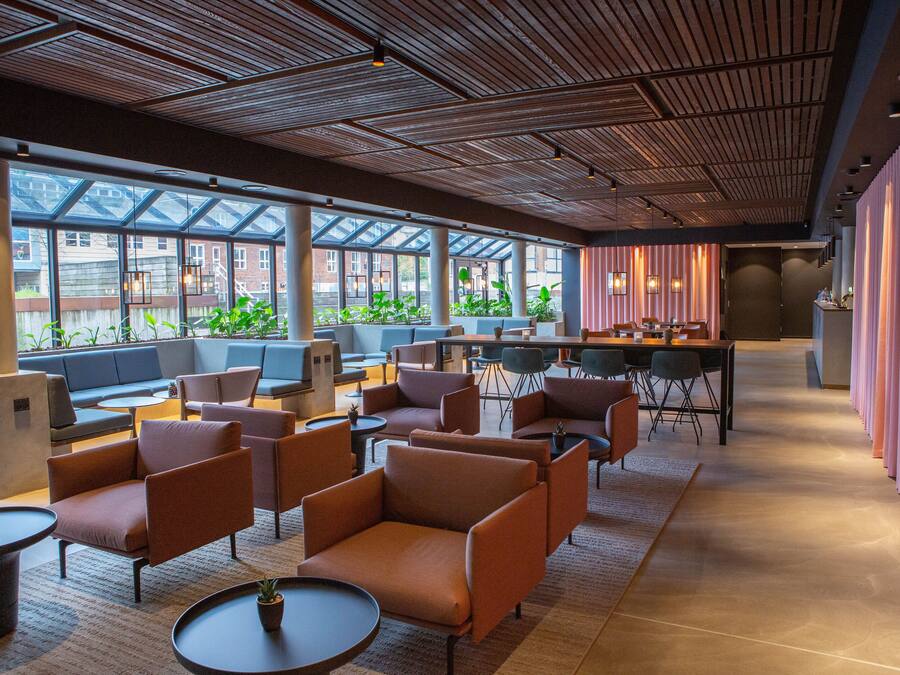 A modern lounge area with comfortable seating, large windows, and a view of the city.