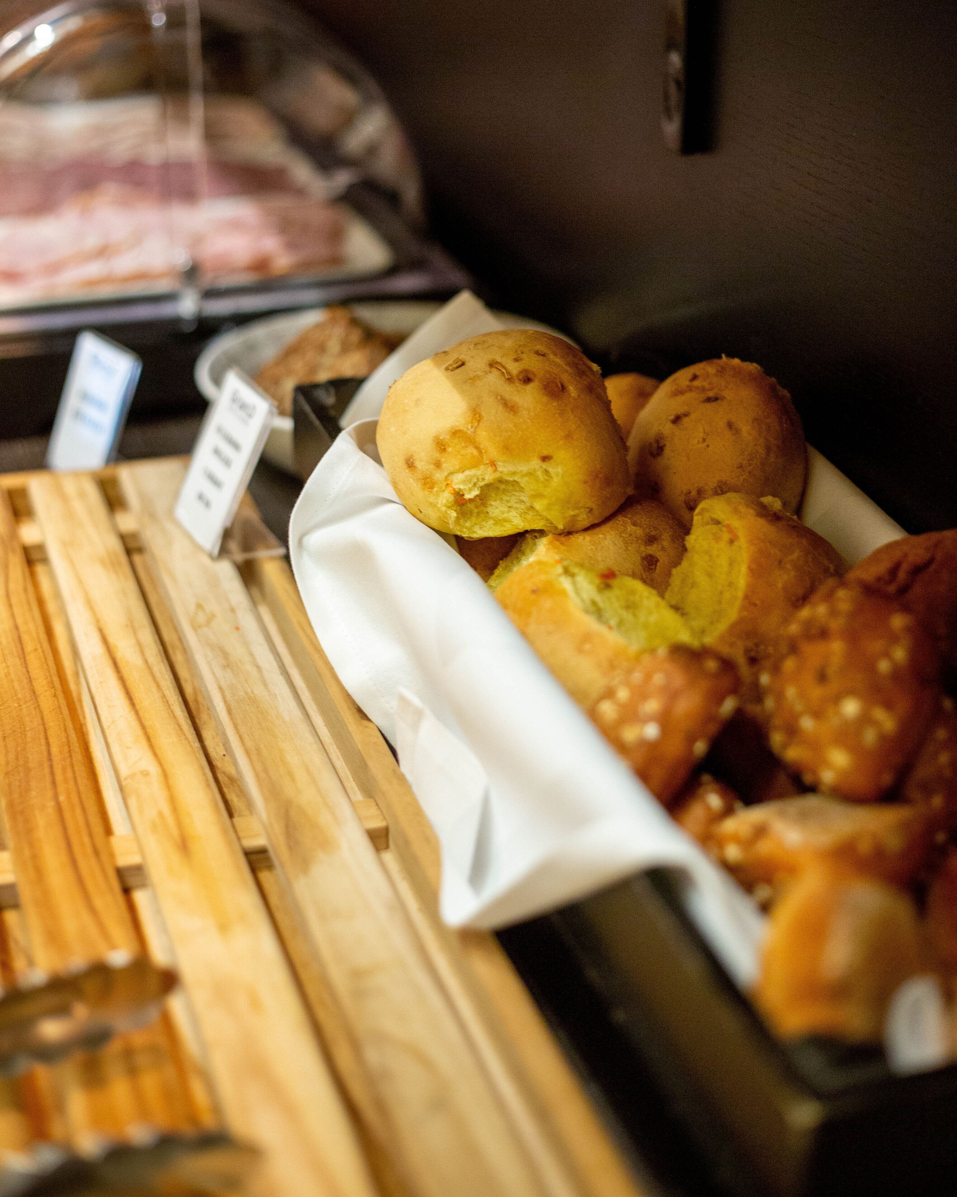 Une vitrine de boulangerie présentant des petits pains et une planche à découper en bois.