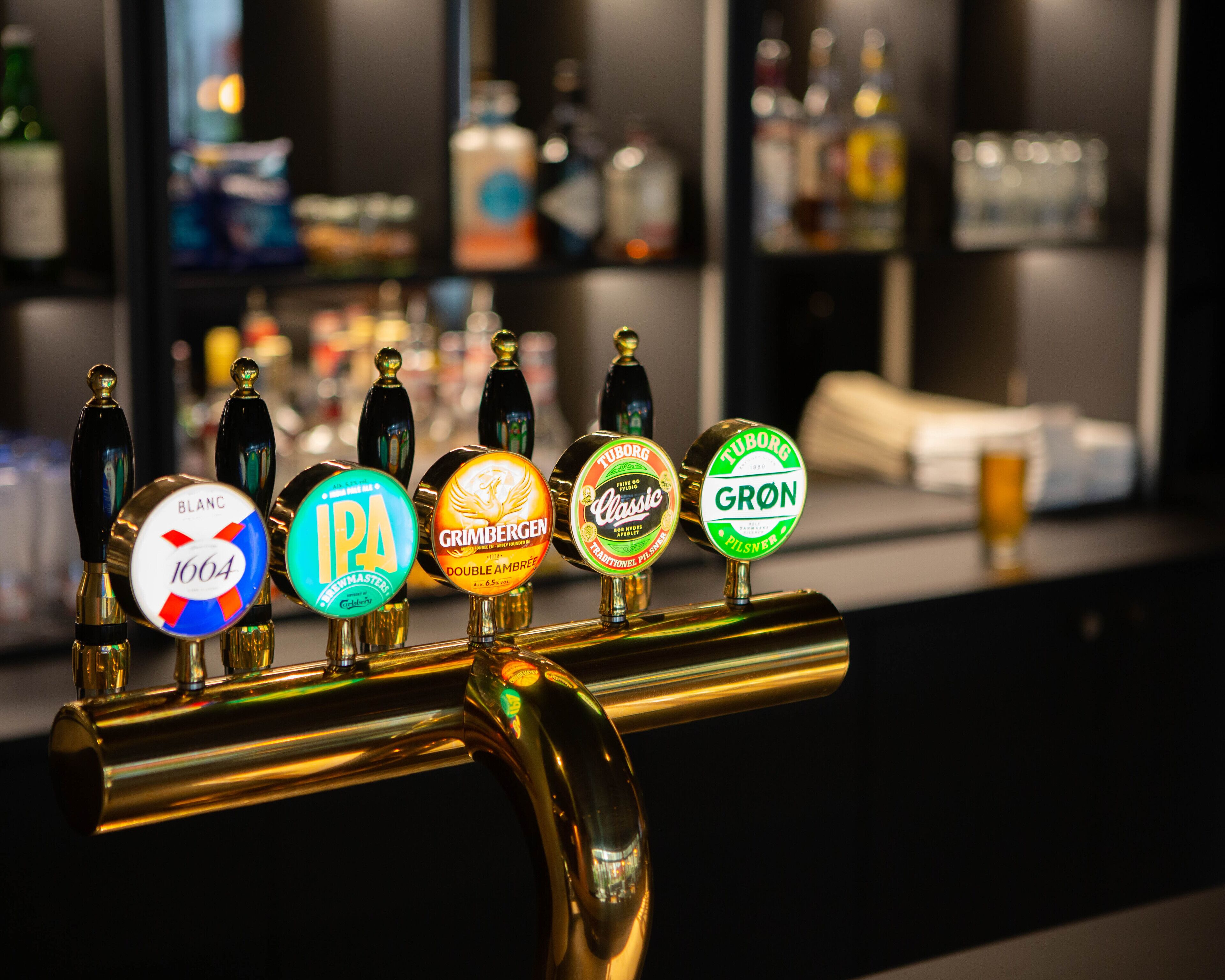 Een bar met een tappunt waarop verschillende biermerken staan.