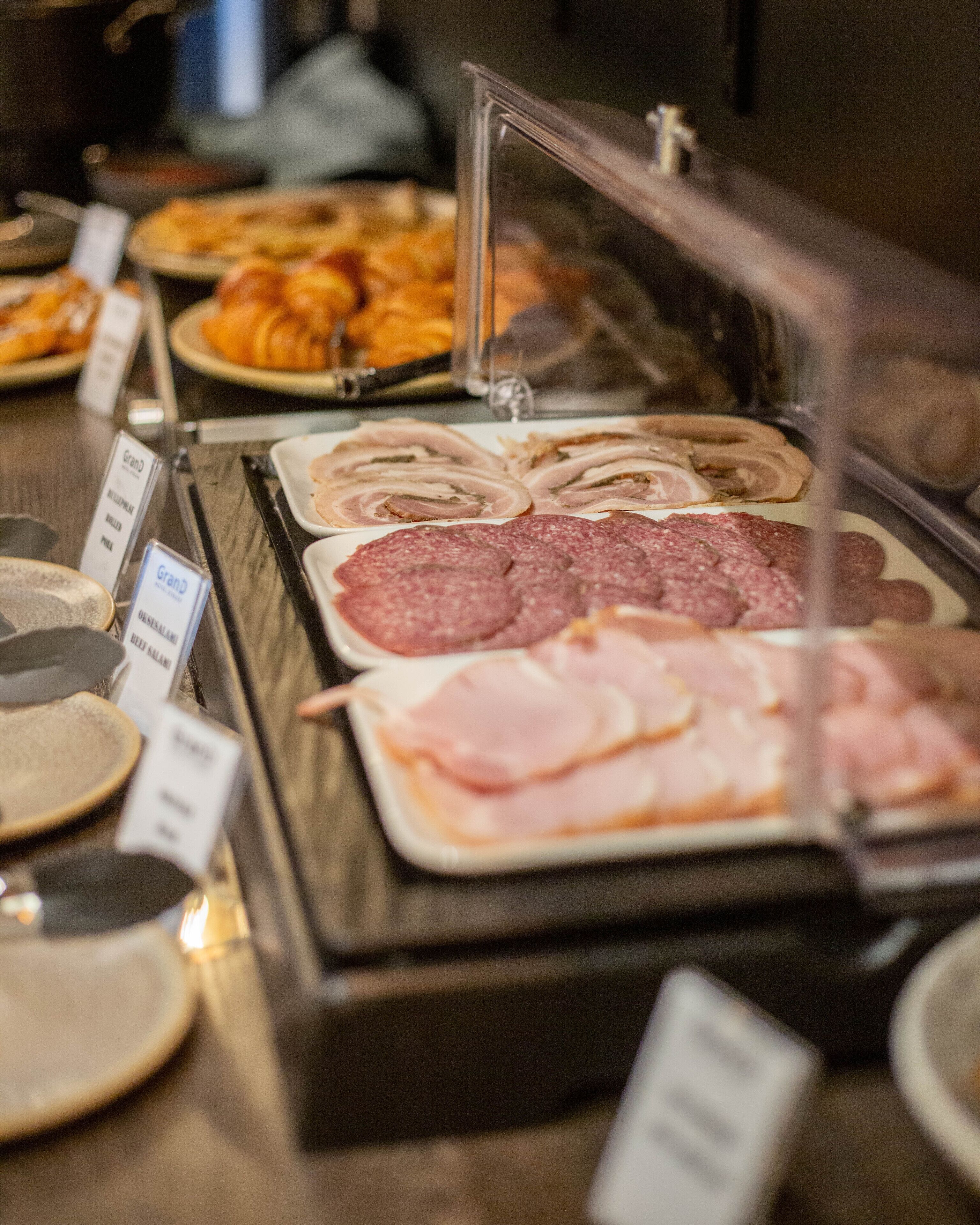 A deli counter with various sliced meats and cheeses displayed in a glass case.