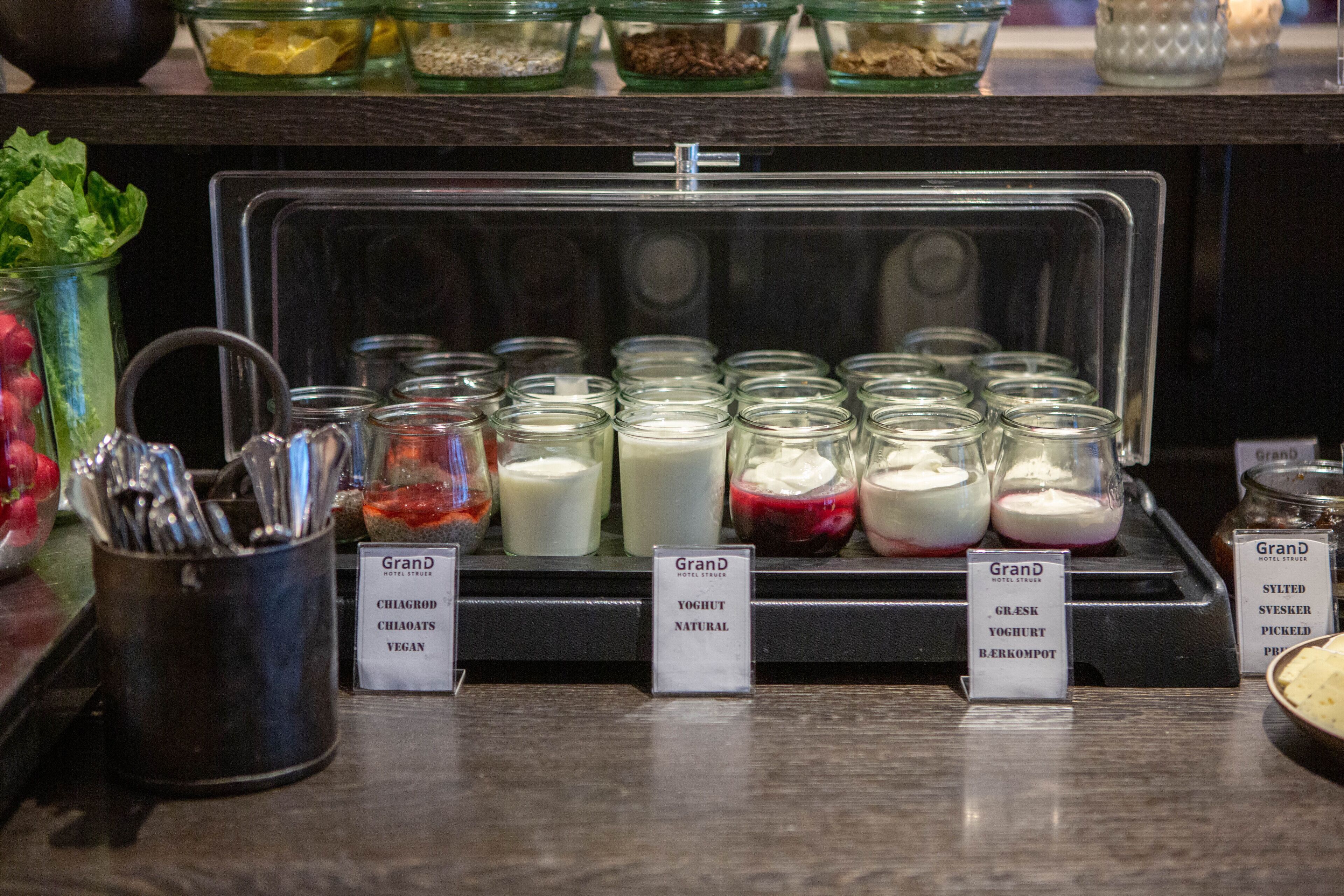 Una exhibición de yogures con diferentes sabores y un cartel que indica opciones veganas.