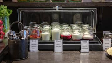 Una exhibición de yogures con diferentes sabores y un cartel que indica opciones veganas.