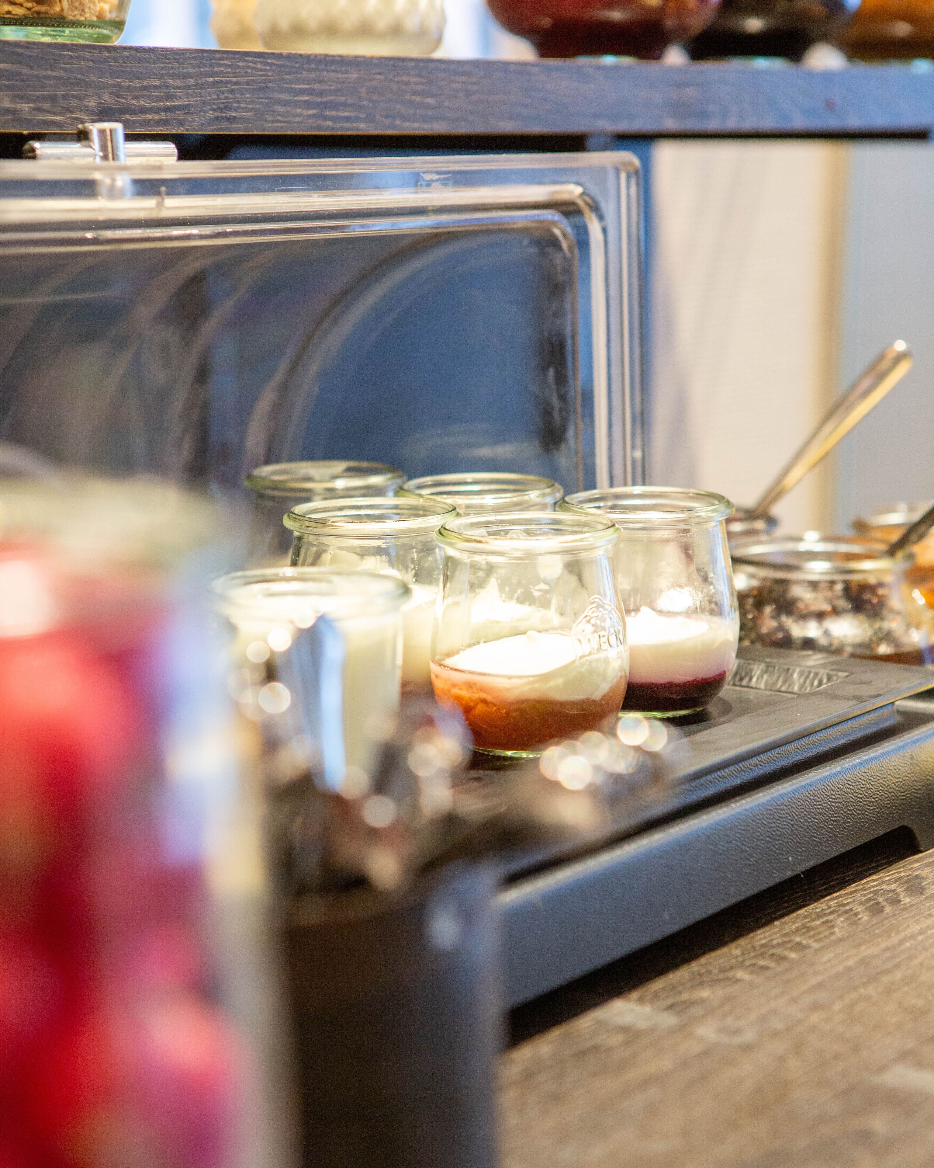 A close-up of a kitchen counter with several glass jars containing food items, a spoon, and a metal container.