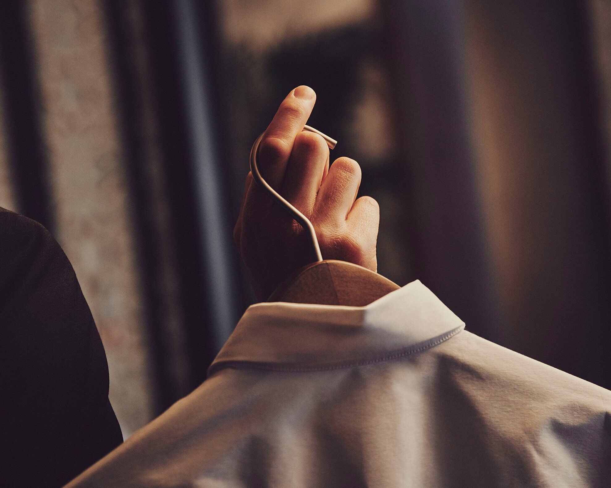 A hand holding a smartphone, with a blurred background suggesting an indoor setting.