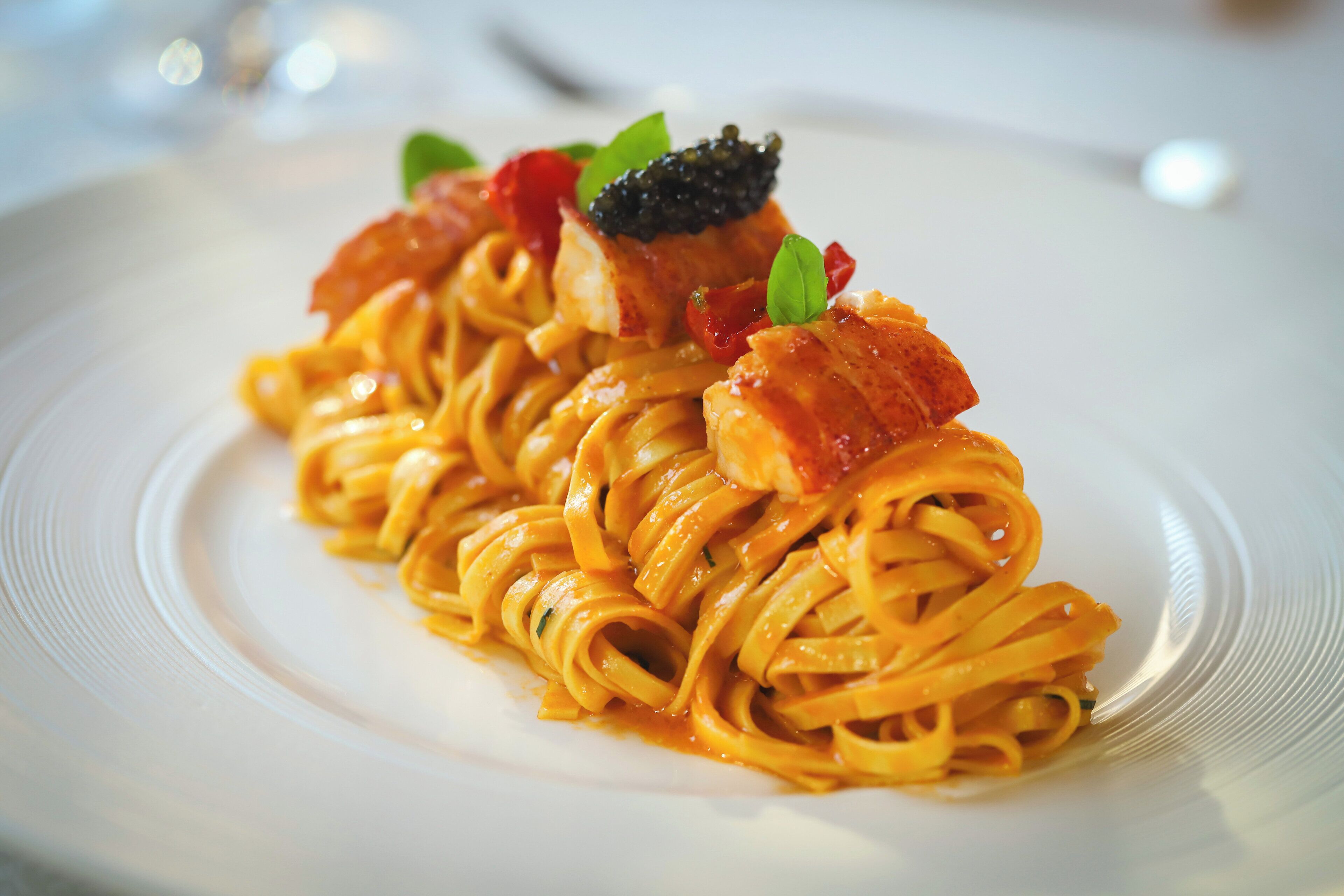 Un plato de pasta con salmón y caviar, decorado con una hoja.