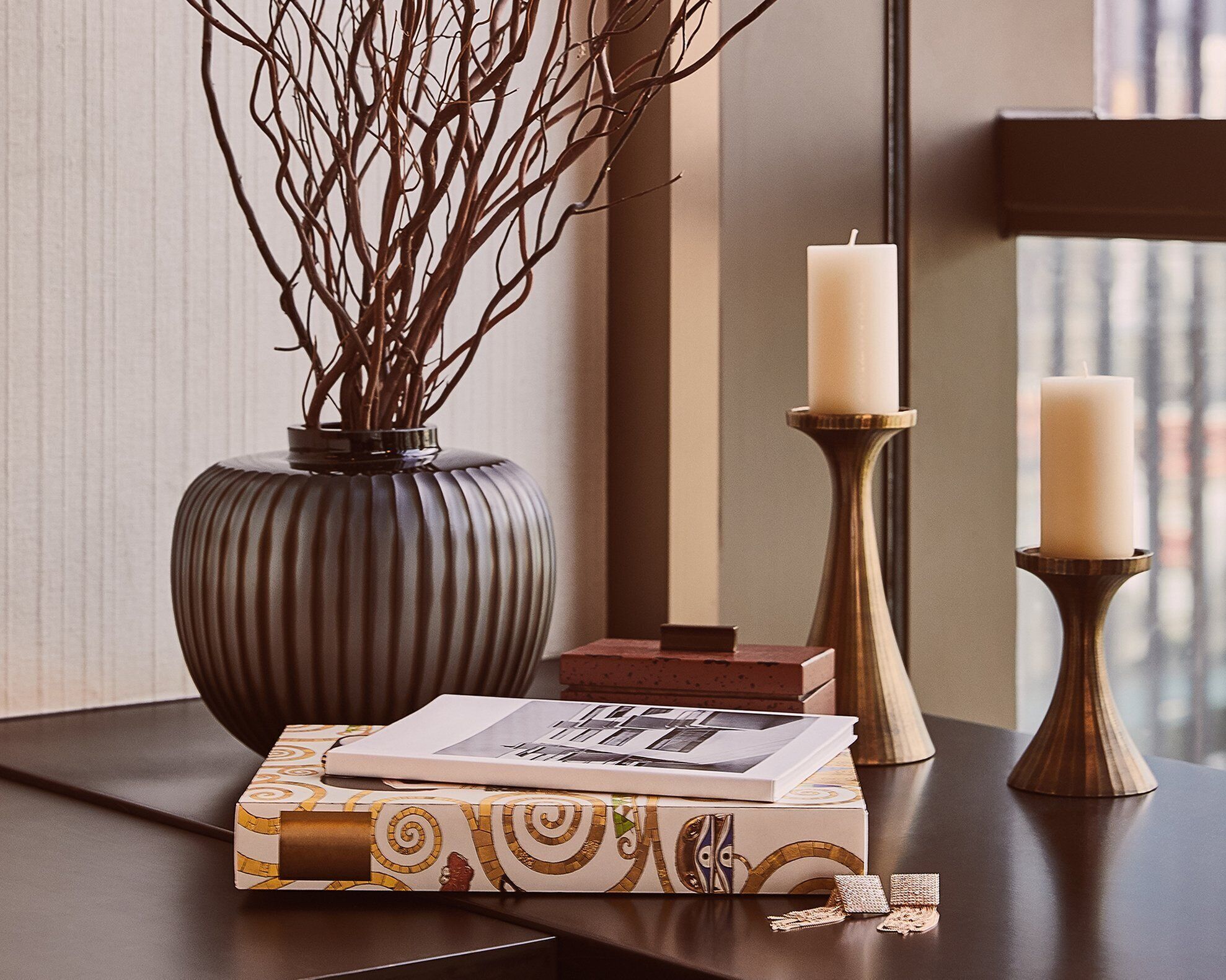 A table with a vase, candles, a book, and a decorative box.