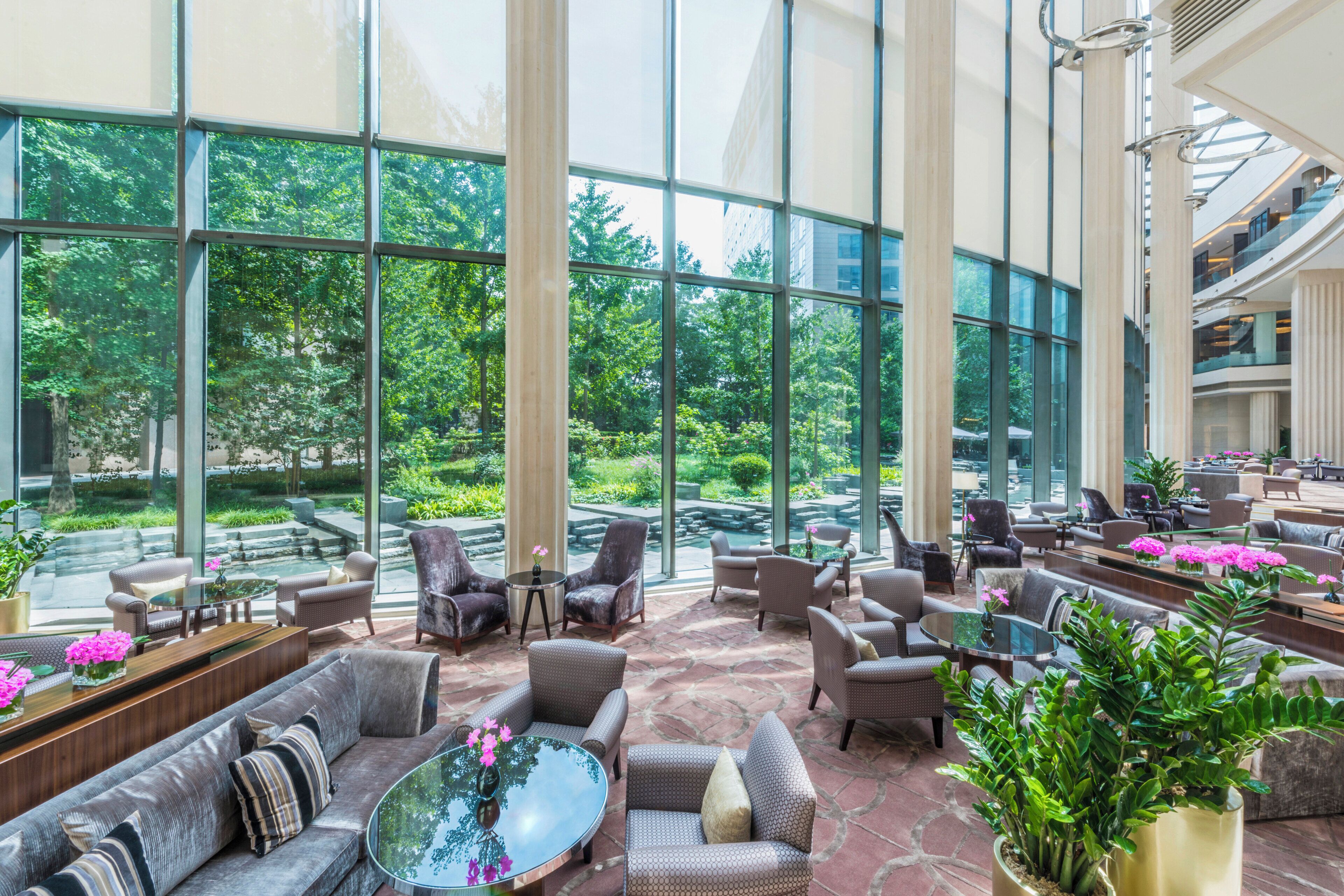 Un espace intérieur vaste et lumineux, doté de grandes fenêtres, de sièges confortables et offrant une vue sur un jardin luxuriant.