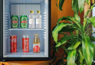 A mini-fridge with beverages including soda cans, water bottles, and a bottle of apple juice.
