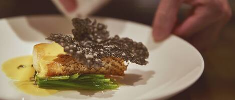A plate with a piece of meat, green vegetables, and a sauce.