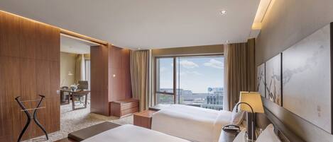A hotel room with two beds, a desk, and a view of the city.
