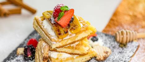 A stack of pancakes with fruit toppings and powdered sugar.