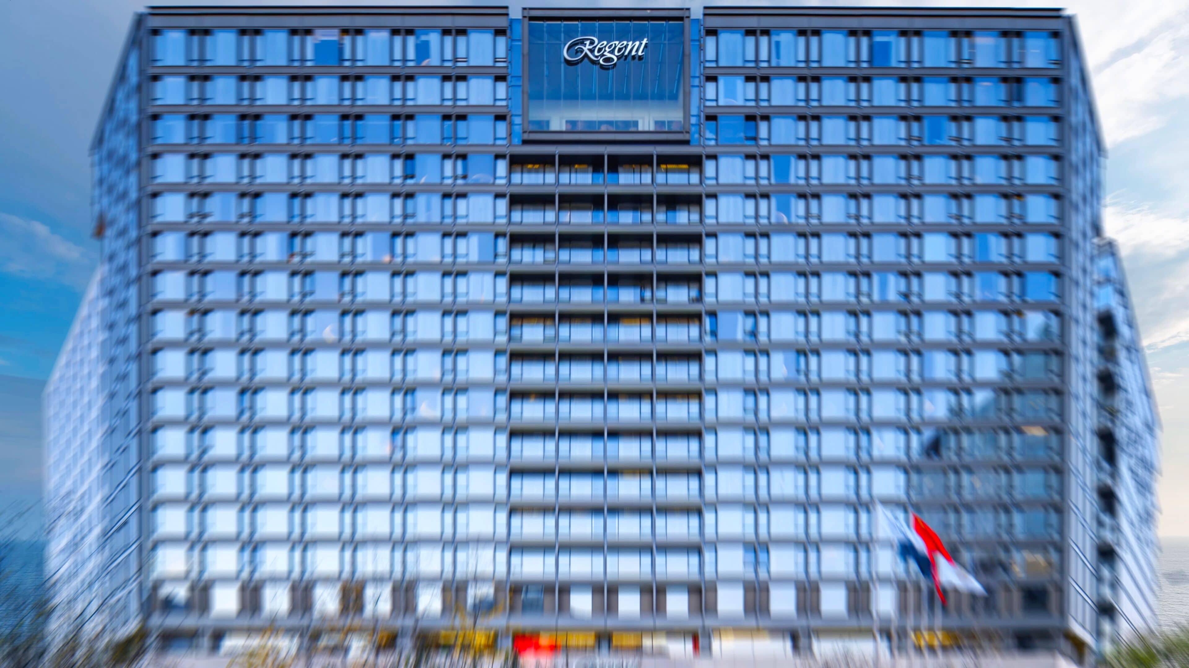A modern high-rise building with a grid of windows and a prominent 'Regent' sign at the top.