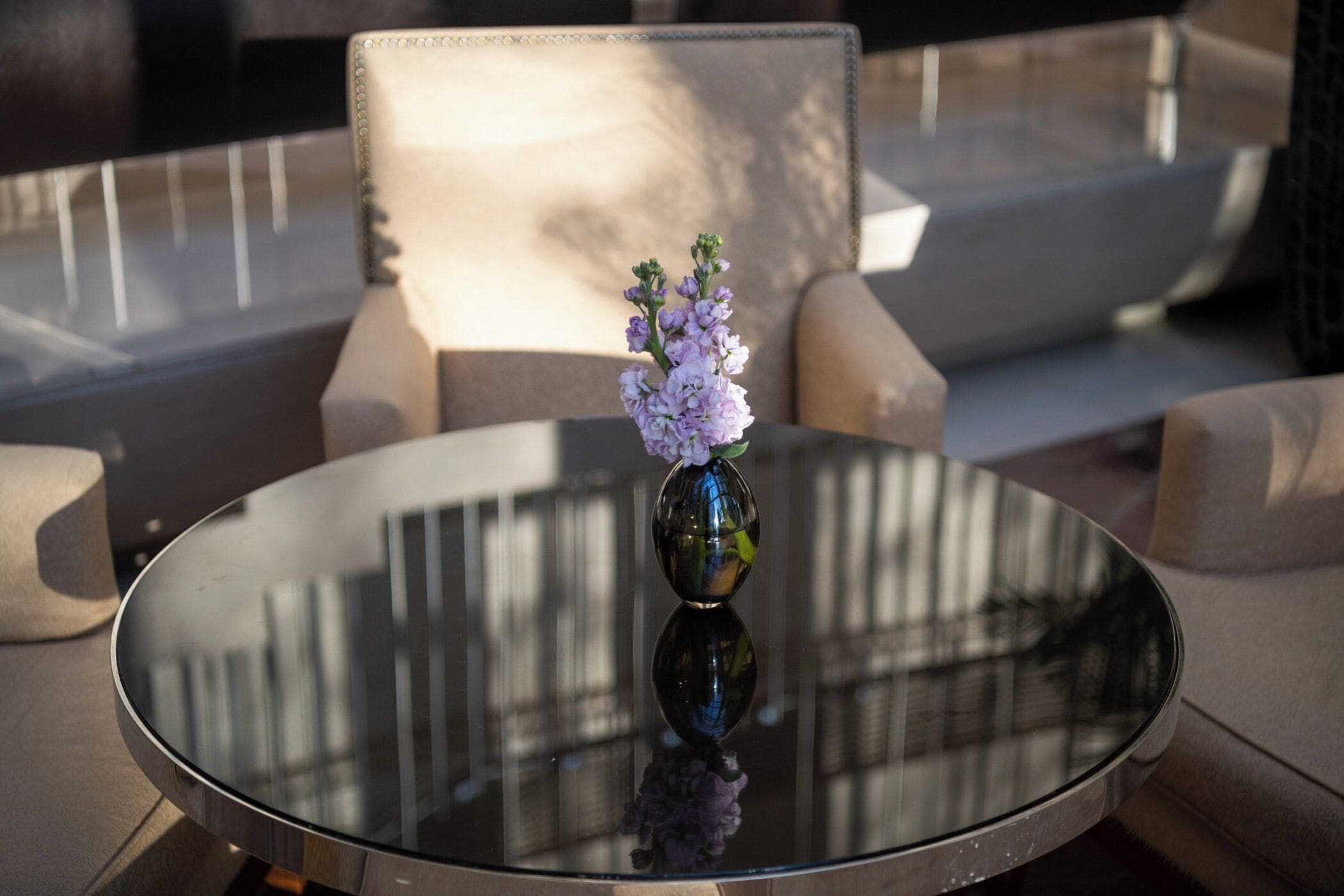 A round glass table with a vase of flowers.