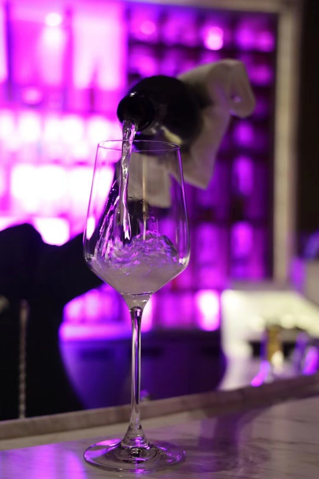 A clear glass of water being poured into a stemmed glass.