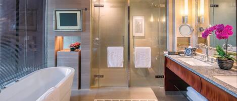 A modern bathroom with a freestanding bathtub, a glass-enclosed shower, and a vanity with a sink and mirror.
