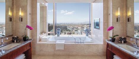 Un baño lujoso con dos lavamanos, una bañera grande y vistas a la ciudad.