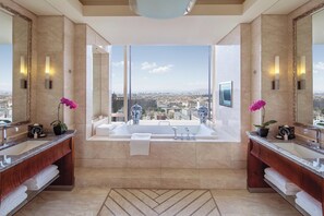 Un baño lujoso con dos lavamanos, una bañera grande y vistas a la ciudad.