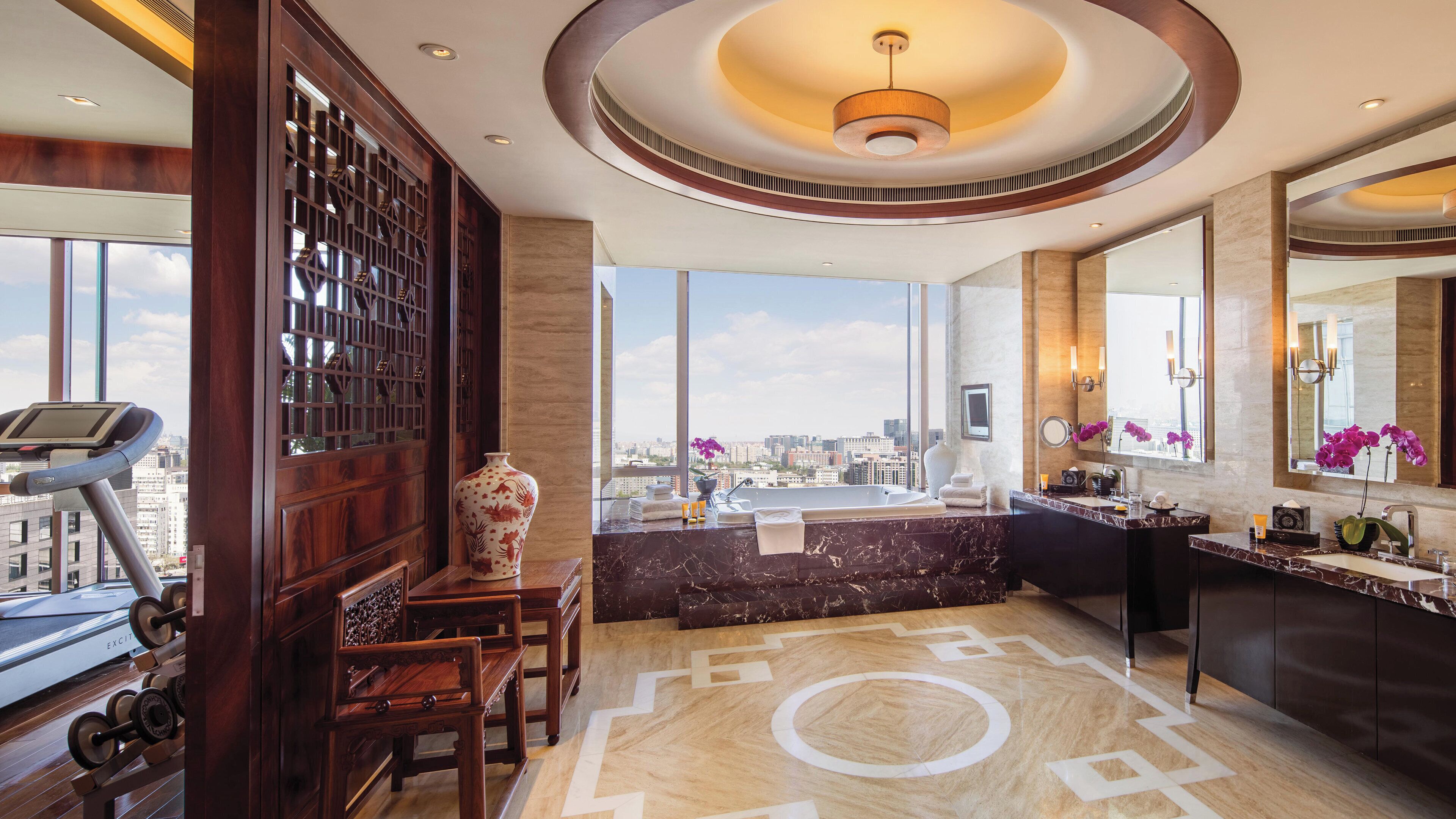 A modern bathroom with a large mirror, a bathtub, and a view of the city.