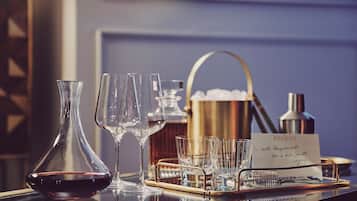 A bar setting with a wine bottle, glasses, a tray, and a sign.