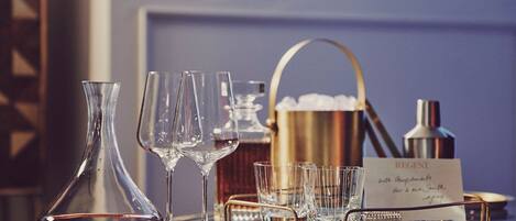 A bar setting with a wine bottle, glasses, a tray, and a sign.