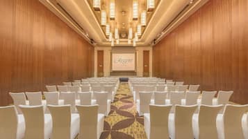 Ein Konferenzraum mit Reihen weißer Stühle, einem Teppichboden und einem großen Bildschirm, der 'Regent Beijing' anzeigt.