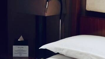 A hotel room with a neatly made bed, a bedside table with a lamp, and a framed picture on the wall.