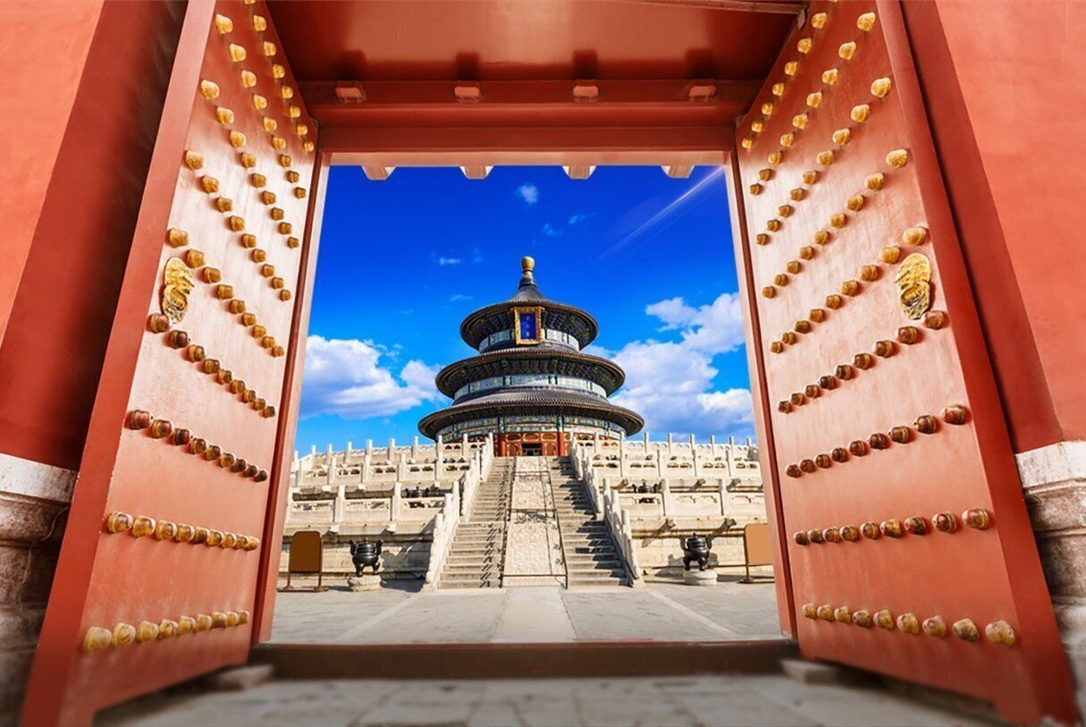 A traditional Chinese gate leading to a pagoda with multiple tiers, surrounded by a stone courtyard.