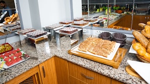Un buffet proposant une variété de plats, notamment du pain, des viennoiseries et des desserts.