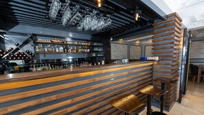 Un espace bar avec des lambris en bois, un comptoir, des tabourets et un présentoir à bouteilles.